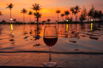 Glass of red wine on luxury resort at sunset