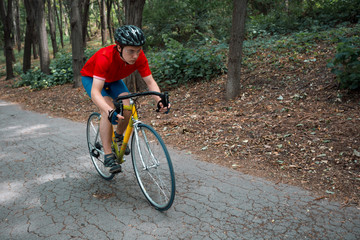 Obraz premium A cyclist rides on a road bicycle on road in woods.