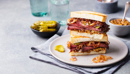 Roast beef sandwich on a plate with pickles. Copy space.