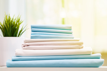 Closeup stack of blue and white clean bedding on the table. Blurred background.
