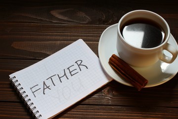 Father inscription and word in a notebook near a cup of coffee