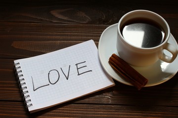 Love inscription and word in a notebook near a cup of coffee