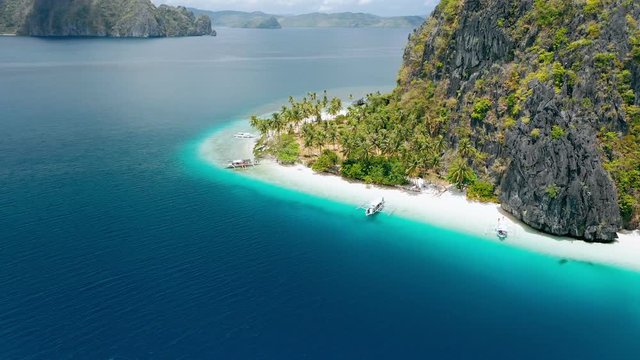 Aerial drone footage of tropical Ipil beach, Pinagbuyutan Island, El Nido, Palawan, Philippines. Turquoise water, sandy beach, palm trees and trip boats - vacation, travel tourism concept