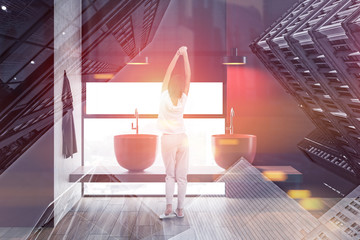 Woman standing in red bathroom with two sinks