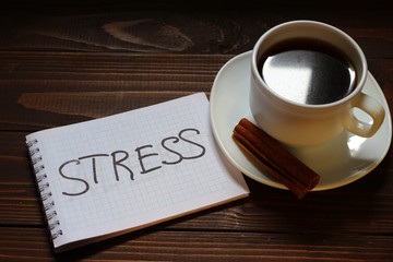 Stress inscription and word in a notebook near a cup of coffee