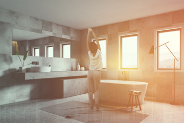 Fototapeta na wymiar Woman in luxury white tiled bathroom corner