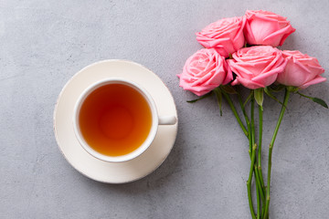 Cup of tea with pink rose. Top view. Copy space. Grey stone background.