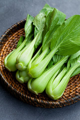 Bok choy fresh salad on wooden plate. Grey background.