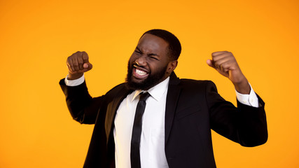 Emotional black businessman celebrating successful deal, making winner gesture