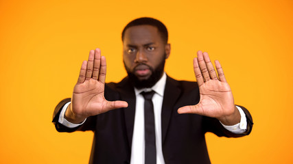 African-american man in formalwear showing stop gesture to racism and inequality