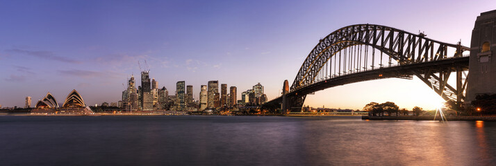 Fototapeta premium Panoramiczny widok na centrum Sydney i most Harbour Bridge o zachodzie słońca
