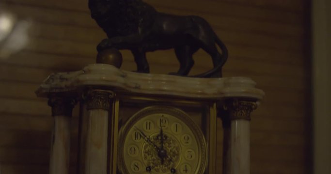 Marble clock with a black lion sculpture in a creepy haunted house on a winter night. Tilt up tight shot. Halloween scary ambiance. Ghost, Demon or Spirit. Shot on RED SCARLET 6K.