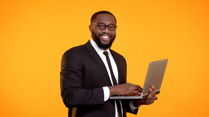 Smiling afro-american businessman working on laptop, career growth, business