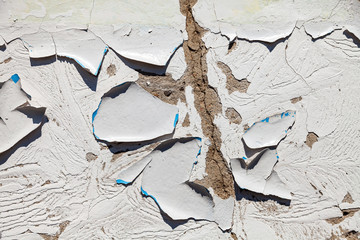 Background with the image of the old white wall with falling off and exfoliated paint and plaster on site of the ruins with a chaotic and chaotic texture requiring repair. Pattern with lime and crack