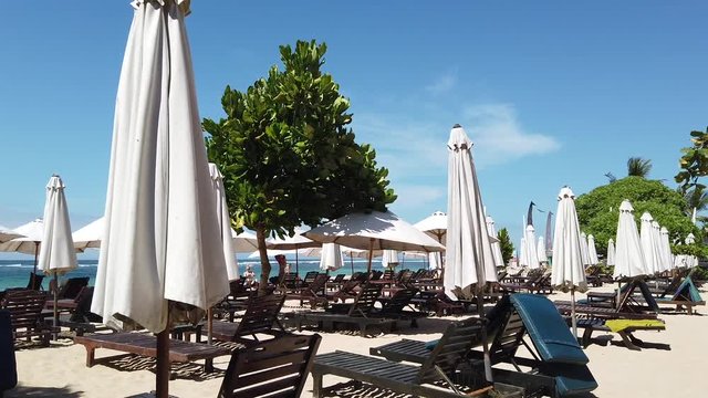 on the beach there are unfilled sunbeds and umbrellas from the sun. the video shows how the wind shakes umbrellas. Indonesia, Bali, Nusa Dua.