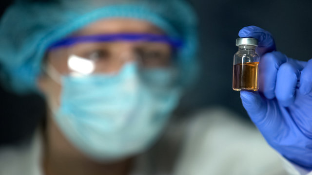 Researcher analyzing transparent brownish liquid in bottle, antidote development