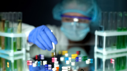 Lab assistant analyzing medication capsules, counterfeit pharmaceuticals, study