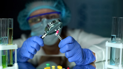 Scientist analyzing capsule with magnifying glass dietary supplement development