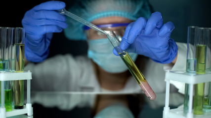Lab assistant dripping oily substance in tube with chicken meat sample, analysis