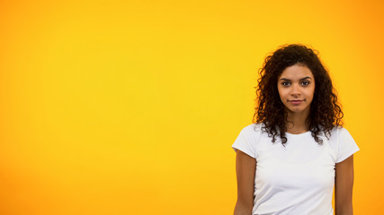 Cheerful African-American woman looking at camera isolated on yellow background