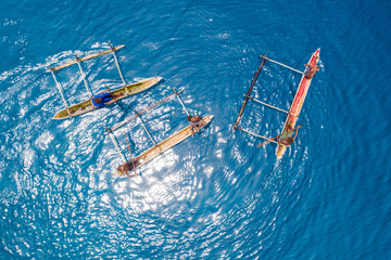 Boys paddle their outrigger canoes in the warm, blue waters of the Pacific Ocean near remote...