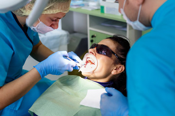 Dentist treating teeth to woman patient in clinic. Female professional doctor stomatologist at work.
