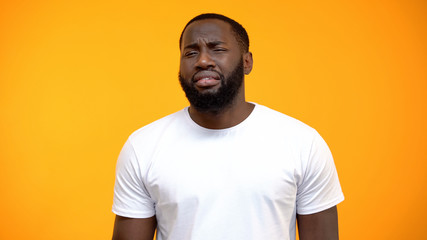 Disappointed Afro-American man looking at camera isolated on yellow background