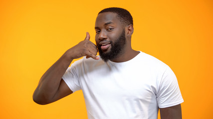 Handsome Afro-American man showing call me gesture, customer services, feed back