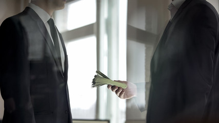Businessman giving his partner cash, profit from successful business deal