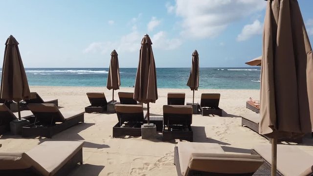 on the beach there are unfilled sunbeds and umbrellas from the sun. the video shows how the wind shakes umbrellas. Indonesia, Bali, Nusa Dua.