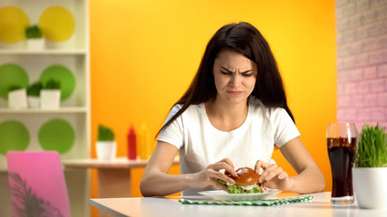 Obraz na płótnie Canvas Upset female customer putting tasteless burger on plate, cheap food quality