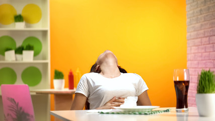 Young woman leaning on chair after meal, sitting at cafe, fast food overeating