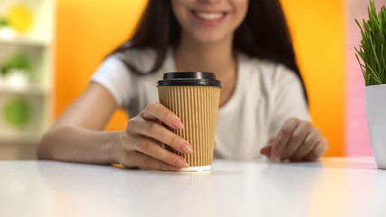 Woman holding hot coffee in paper glass and smiling, morning energy, break