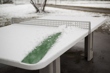 A table tennis with snow in the street.
