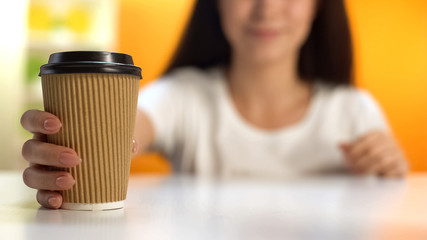 Female holding cup of coffee, morning beverage, take away from cafeteria