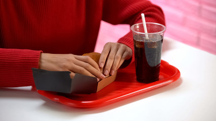 Lady holding hamburger with soft drink, junk food nutrition, fat meal, calories