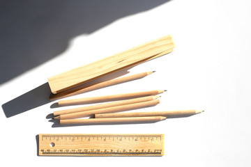 Pencil case and pencils are lying on the table in bright daylight. Natural unpainted wood. Eco-friendly materials