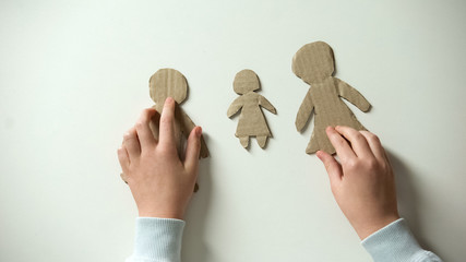 Child putting paper family on white background, orphan needs home, adoption