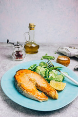 Salmon steak and green salad with cucumber, broccoli and peas.
