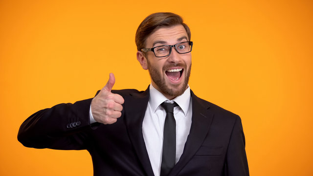 Smiling businessman showing thumbs up at camera, making good proposition