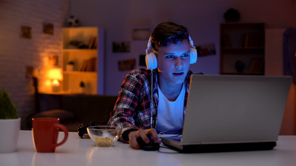 Bored teenager surfing internet, eating snacks and wasting time, procrastination