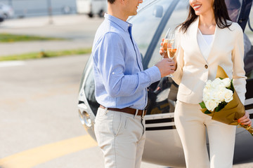 cropped view of husband and wife clinking champagne glasses on romantic date near helicopter