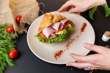 Breakfast croissant sandwich with ham and cheese. Top view. black background with vegetables....