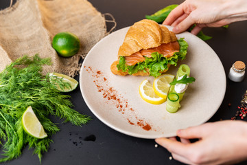 Breakfast Croissants with soft cheese, salted salmon and green salad. Love. Top view. black background with vegetables. Slow-mo.