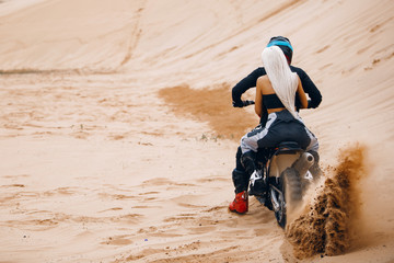 Couple of bikers riding cross motorcycle on the desert . Rider with a woman go fast at Dubai desert