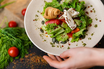 Greek salad of fresh cucumber, tomato, sweet pepper, lettuce, red onion, feta cheese and olives with olive oil. Healthy food, top view. Black background . Slow-mo.