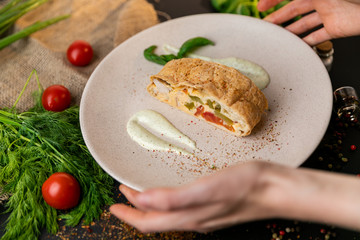 Large portion of healthy colorful vegetable lasagne made with assorted fresh veggies layered with melted mozzarella and pasta served on a white plate. Black background . Slow-mo