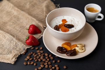 Tasty breakfast. Top view of a bowl of muesli with oats, nuts and dried fruit on black table. Slow-mo.