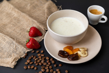 Tasty breakfast. Top view of a bowl of muesli with oats, nuts and dried fruit on black table. Slow-mo.