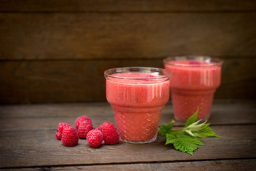 Raspberry smoothie and organic raspberries on rustic wooden table